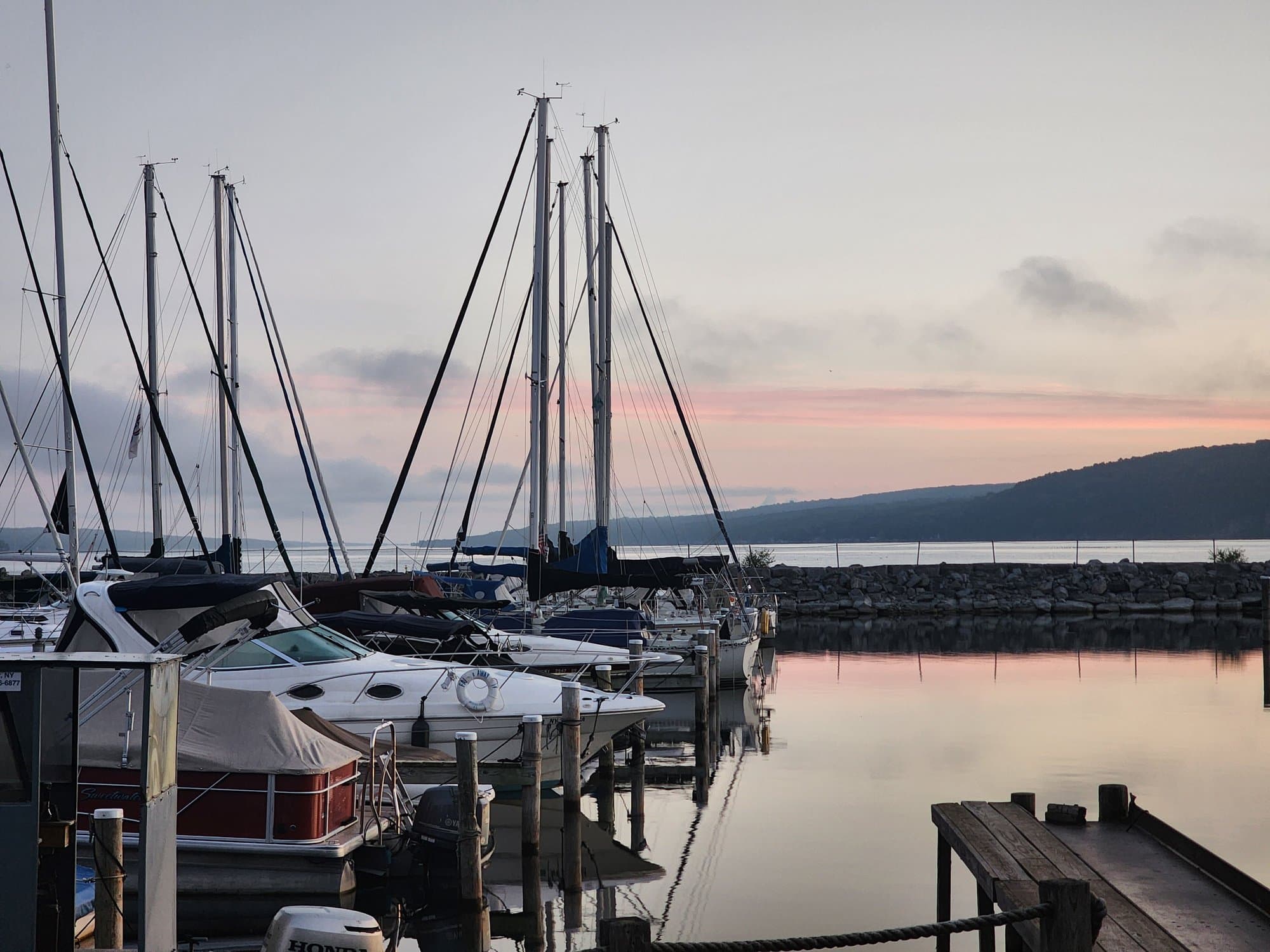 Boats moored at a quiet marina under a dawn sky